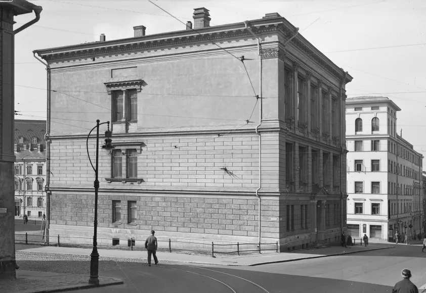 Mustavalkoinen valokuva kolmikerroksisesta kivitalosta.