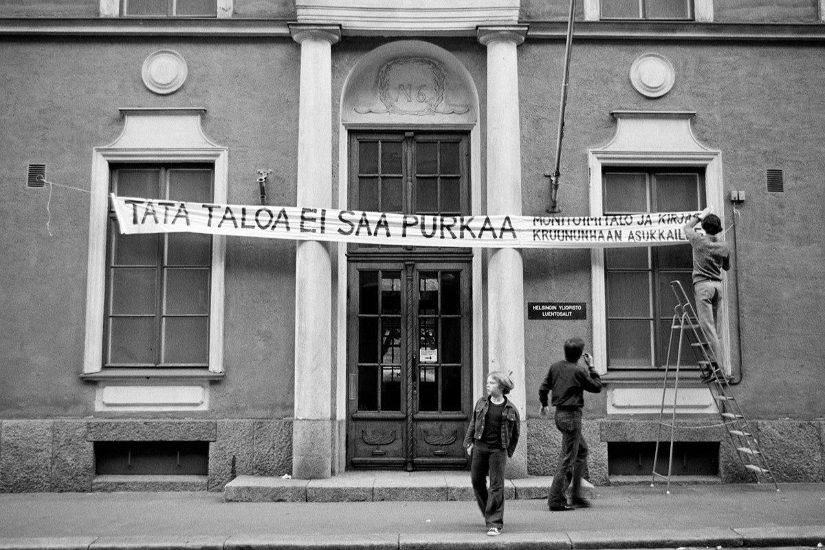 Byggnadsfasad med en banderoll med texten "Tätä taloa ei saa purkaa".