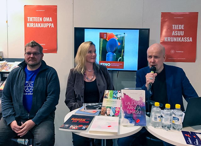 Kolme henkilöä edustavat Suomen etnomusikologinen seuraa Helsingin kirjamessuilla 2019.