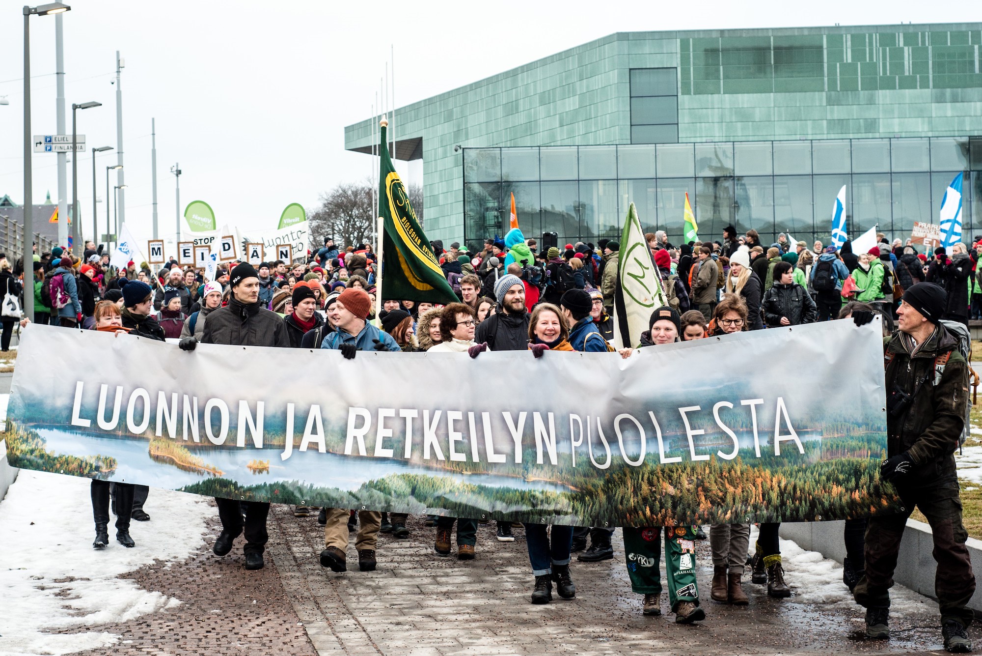 Kuvassa ihmiset marssivat luonnon ja retkeilyn puolesta.