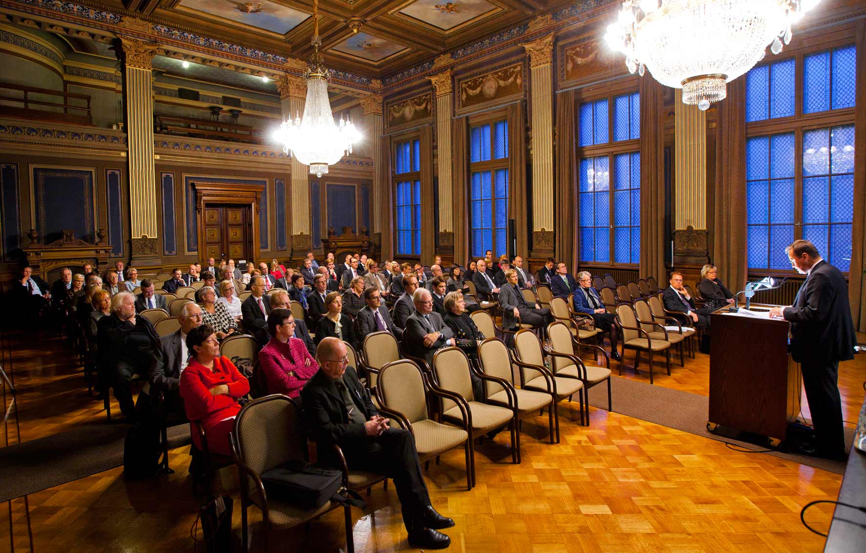 Människor sitter och lyssnar på ett tal.