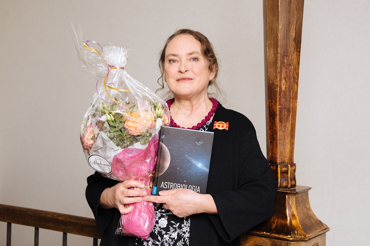 Kirsi Lehto sylissään palkintokukkia ja kirja Astrobiologia.