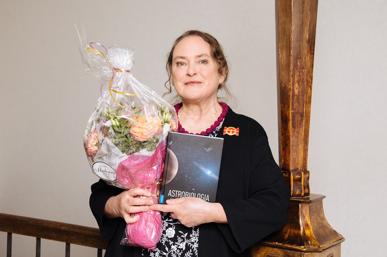 Kirsi Lehto med blommor och boken Astrobiologia i famnen.