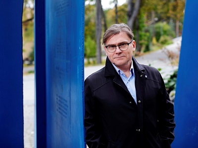 Miesoletettu henkilö tummassa takissa ulkoilmassa.