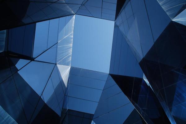 Sininen taivas pilkottaa modernin toimistorakennuksen keskeltä. Kuva: Unsplash, Hector J. Rivas