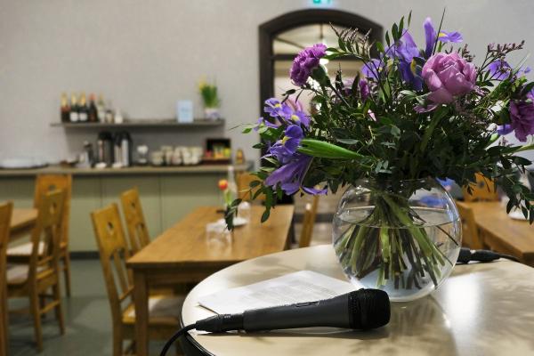 Kukkia lasimaljakossa ja mikrofoni pöydällä.